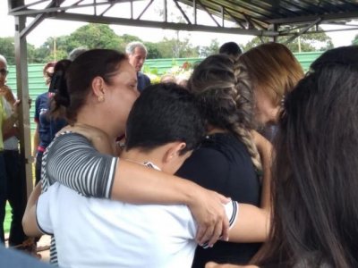 Elaine (trana) abraada ao filho e amigas durante o sepultamento.