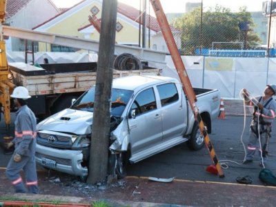 Frente do veculo ficou destruda; funcionrios da Energisa trabalham na troca do poste (Foto: Henrique Kawaminami)