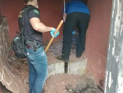 Policiais civis cavando cama de concreto onde ossada foi encontrada. (Foto:Divulgação/Polícia Civil)
