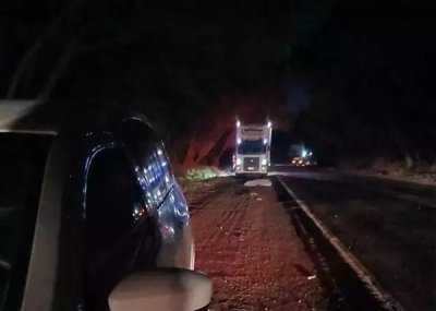 Corpo da vtima coberto com lenol no acostamento da rodovia e logo atrs caminho envolvido no acidente (Foto: Direto das Ruas)